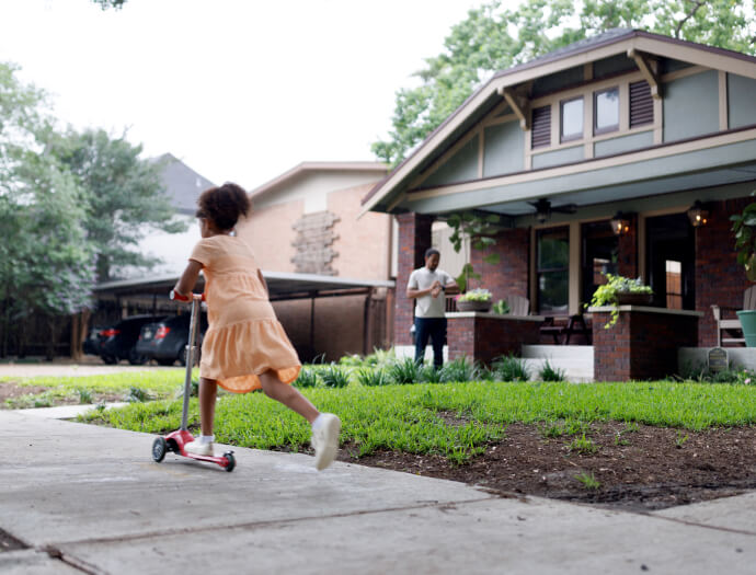 Young girl on scooter in front of house